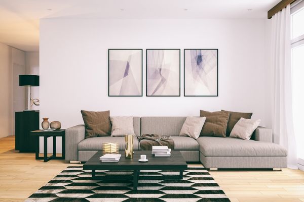 Bostad städad och fixad med hjälp av visningsstädning inför försäljning. Grå soffa med bruna och beige kuddar, svart bord och inredningsdetaljer.